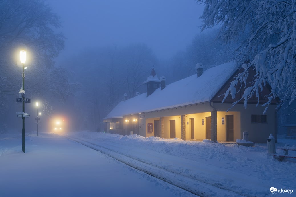Havas, téli hangulat kék órában egy érkező vonattal, Csillebércen