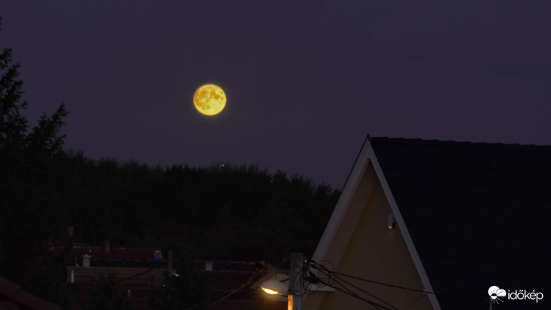 A pár perce felkelő Hold a házak között.