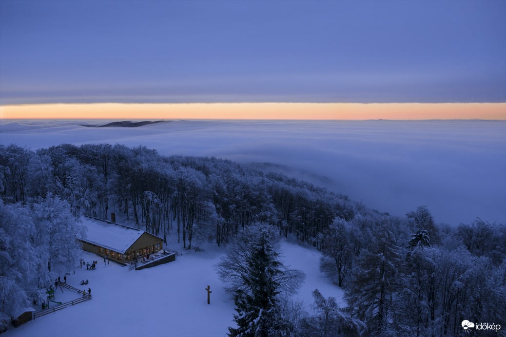 Téli mesevilág naplementekor két felhőzet között Kékestetőn.