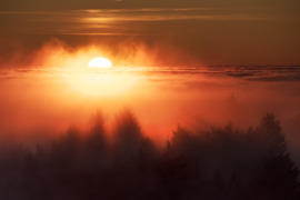 Színpompás, tüzes naplemente a ködtenger határán